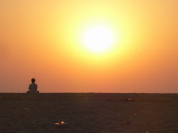 Une femme en pleine méditation sur une plage de Goa